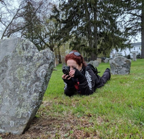 Breand Sullivan of Gravestone Girls takikng a photo of a gravestone.