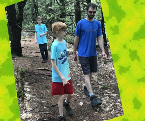Two young boys hiking in the woods with their guardian. Cover image of the author’s book.