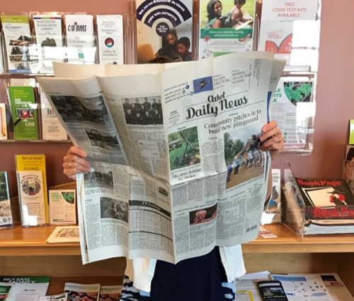 Patron reading a newspaper at the library.