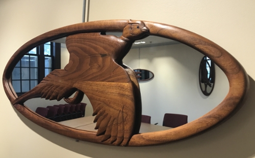 An oval wooden mirror with a wooden bird.