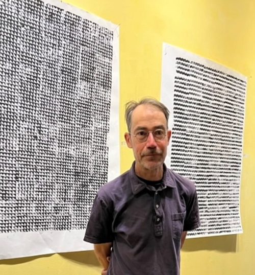 Image of the artist John Armstrong in front of one of his art pieces.